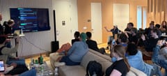 Attendees sit on couches watching a presenter's terminal on a TV during the Effect 4.0 launch talk in San Francisco.